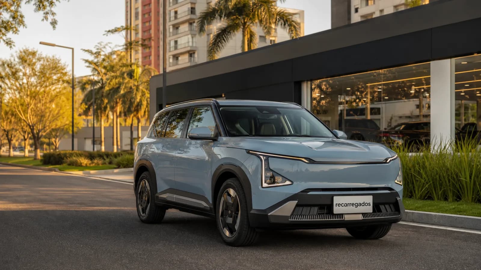 SUV elétrico Kia EV5 em avenida brasileira com placa recarregados em destaque