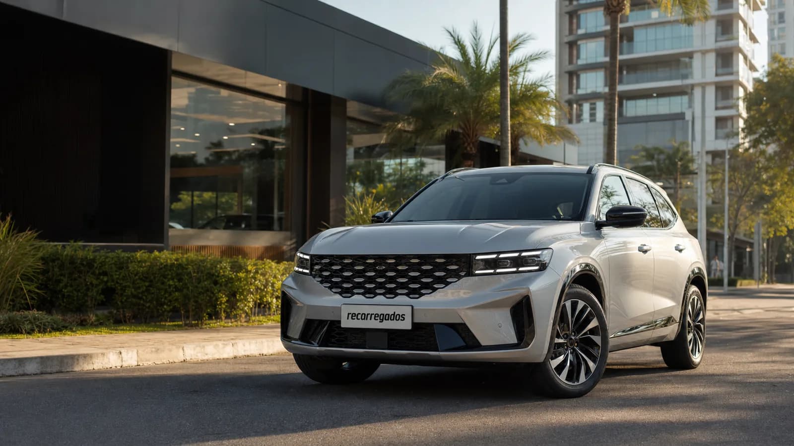 SUV híbrido Renault Koleos em avenida brasileira com placa recarregados em destaque