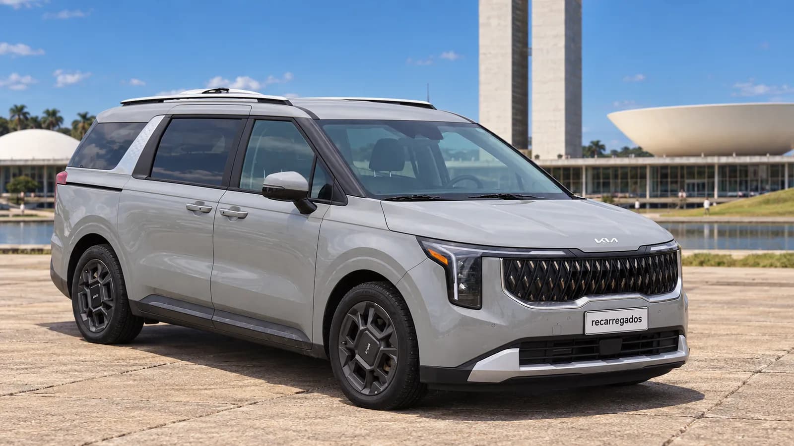 Kia Carnival Hybrid cinza diante da arquitetura modernista de Brasília, imagem gerada com IA a partir de foto real