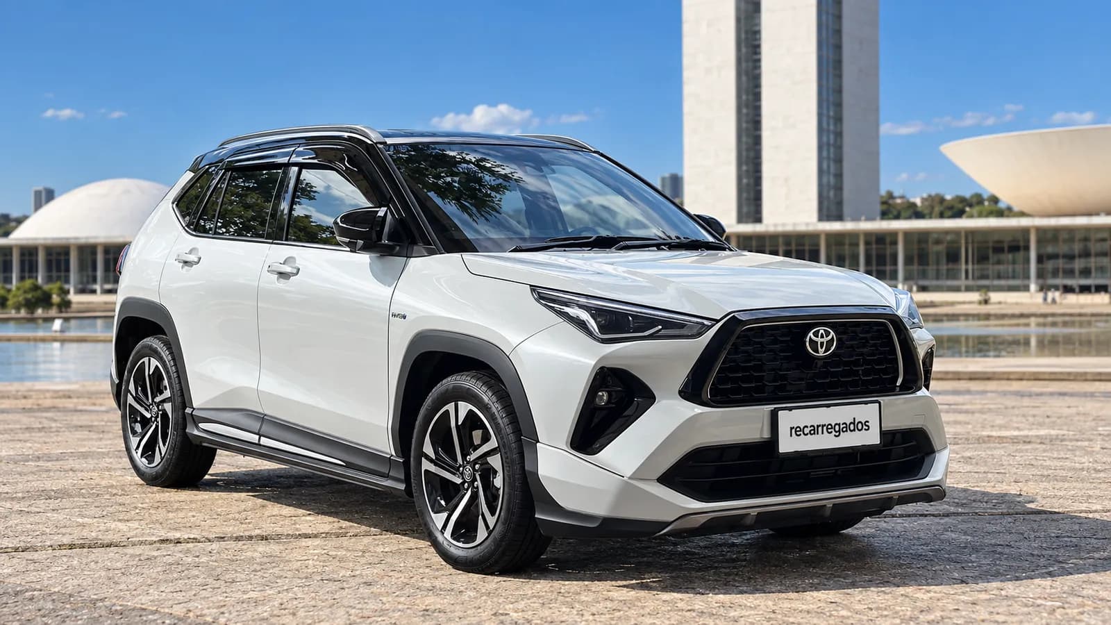 Toyota Yaris Cross Hybrid branco diante da arquitetura modernista de Brasília, imagem gerada com IA a partir de foto real